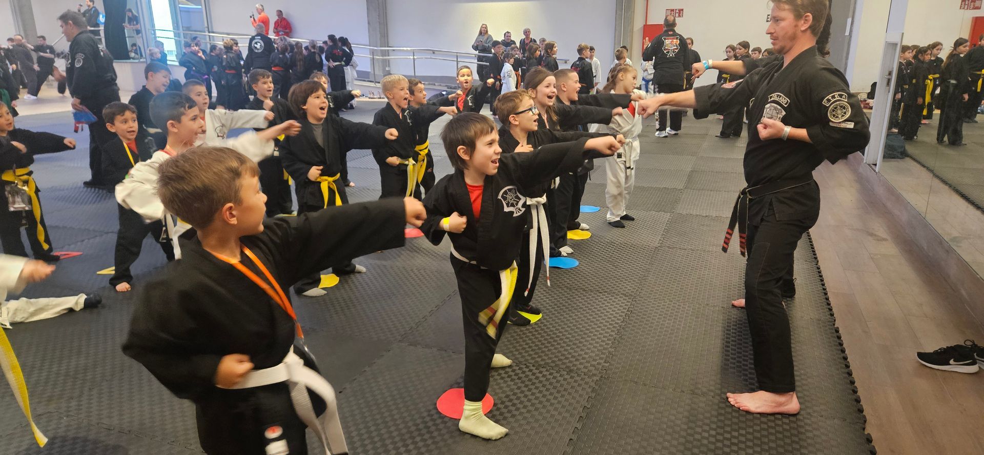 Children in karate class practicing punches, instructed by an adult in a dojo.