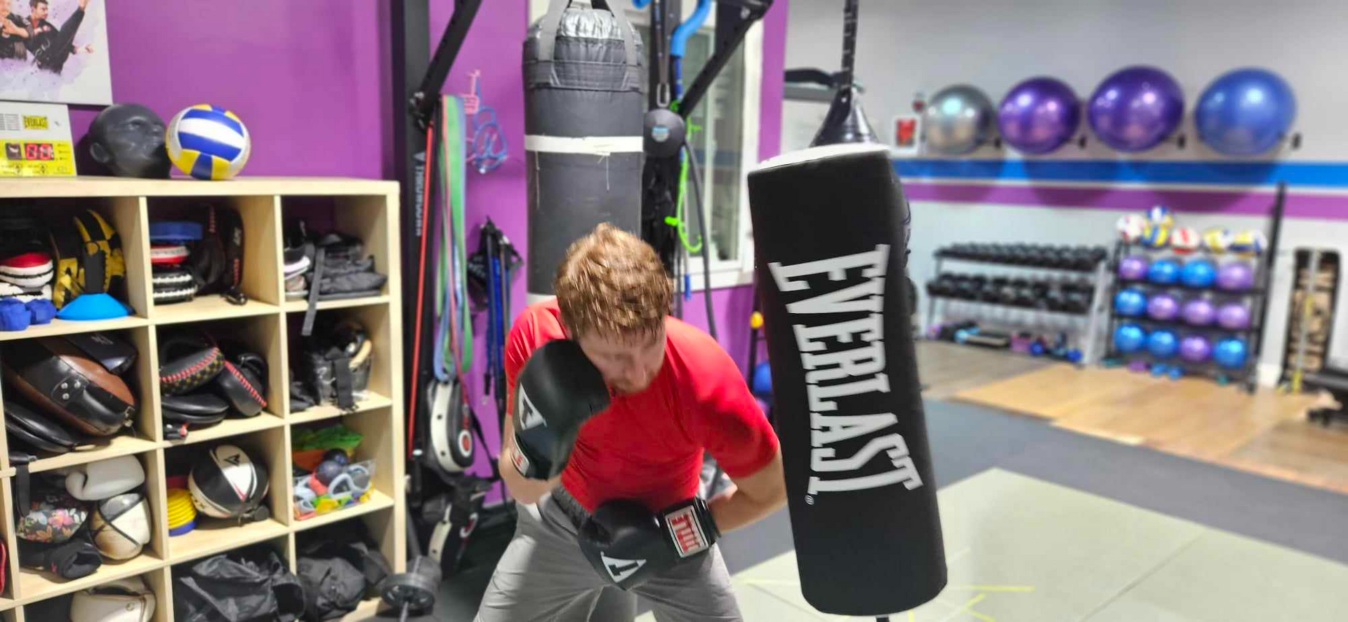 A man is standing next to an everlast boxing bag in a gym.