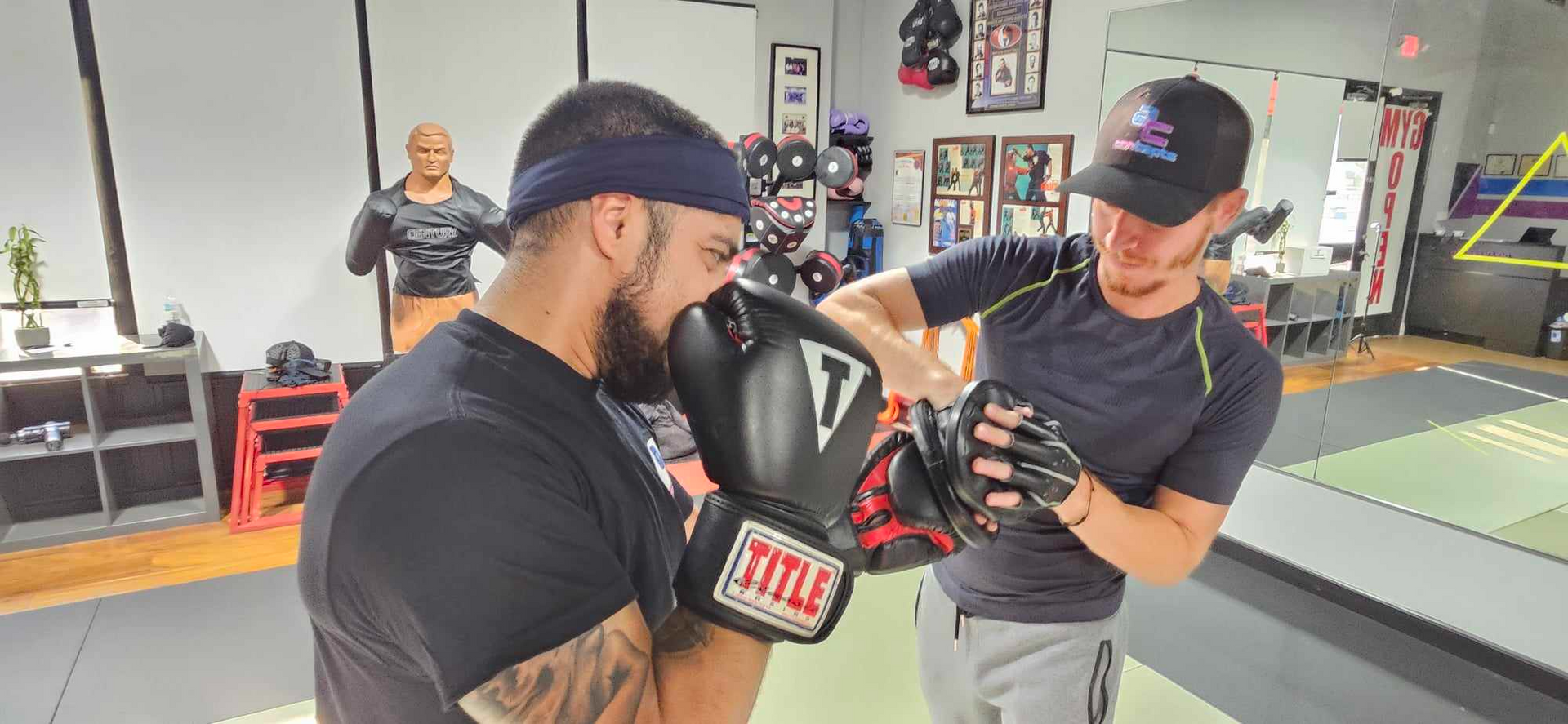 Two men are boxing in a gym and one of them is wearing boxing gloves.