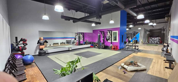 A large gym with a lot of equipment and a purple wall.