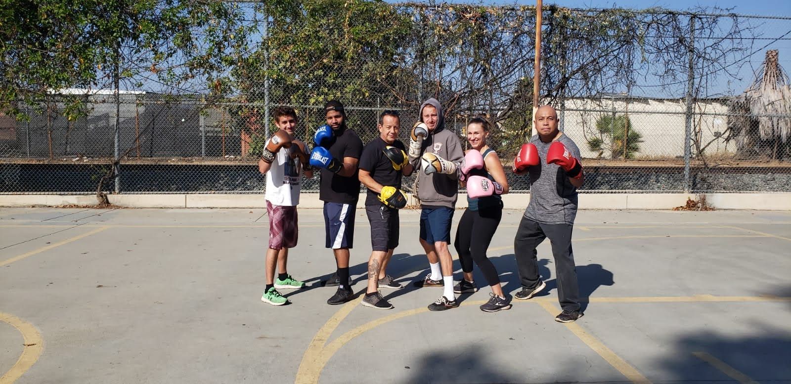 A group of people boxing in an outdoor space, wearing gloves.