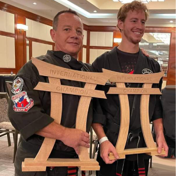 Two men are holding a wooden sign that says international champion