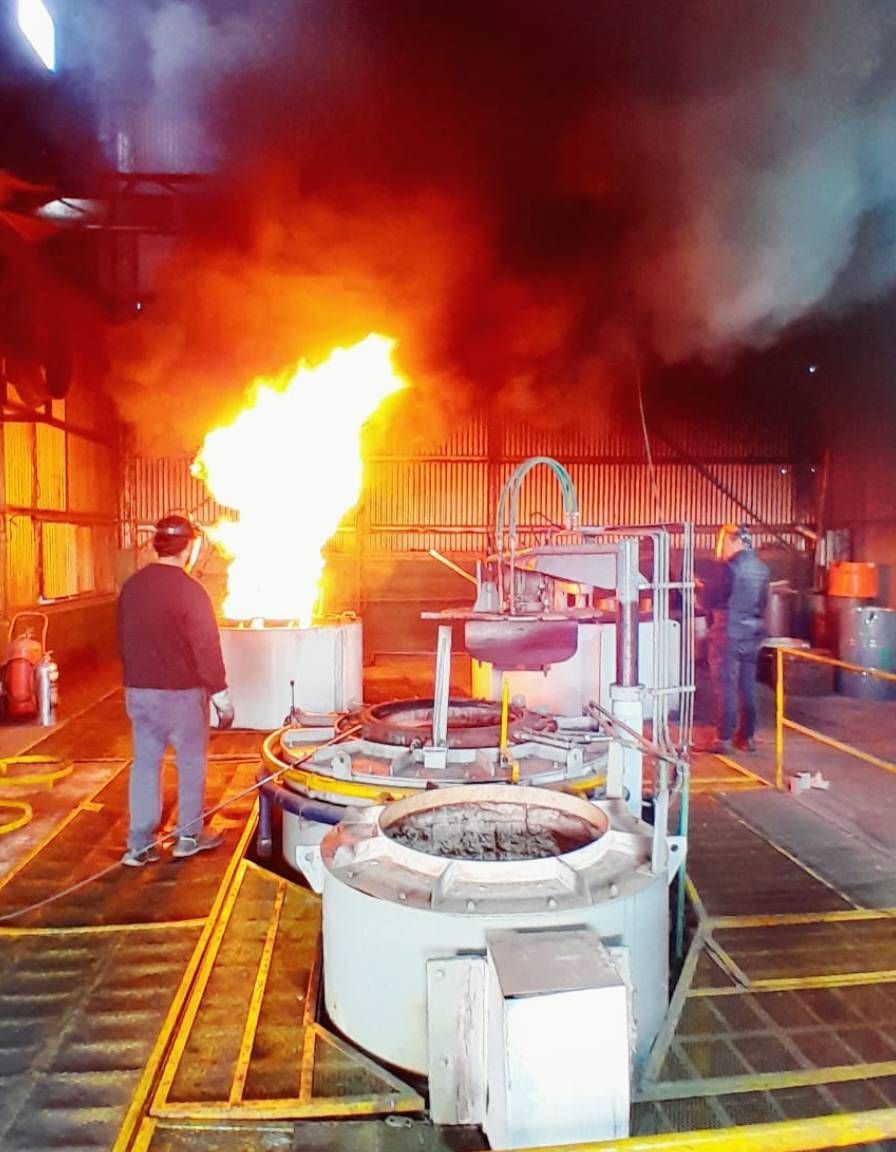 Obrero de fábrica cerca de un gran incendio industrial, con llamas y humo elevándose junto a la maquinaria.
