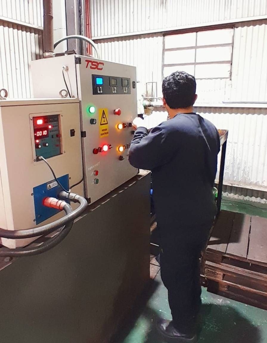 Un operario maneja un panel de control en una sala industrial con luces indicadoras encendidas.