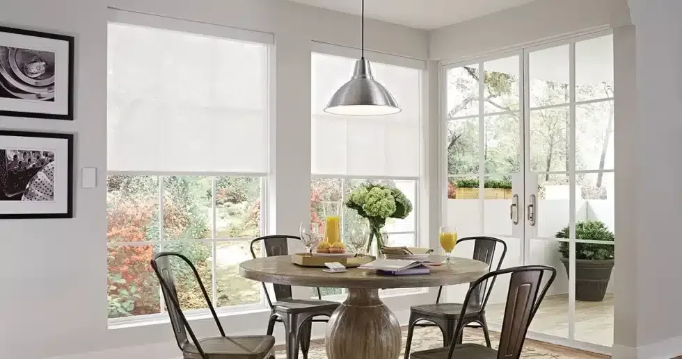 Dining room with round table, metal chairs, white blinds, and a pendant light.