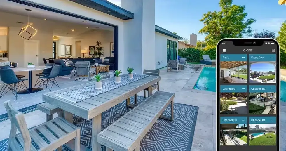 Outdoor patio with a table, benches, and pool; phone shows security camera view.