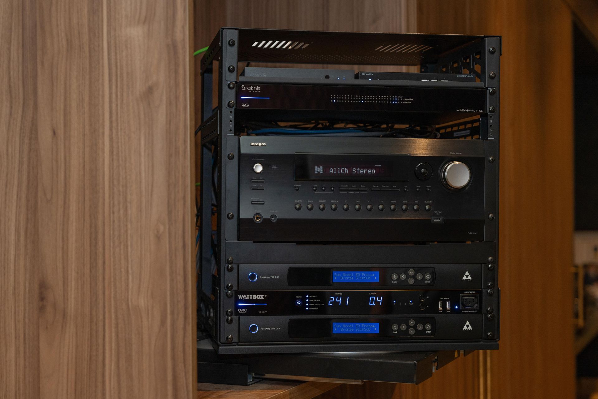 Black AV equipment rack mounted on a wooden wall, containing various electronics.