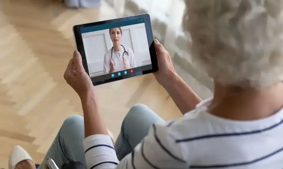 Woman in wheelchair during telehealth appointment with doctor on tablet.