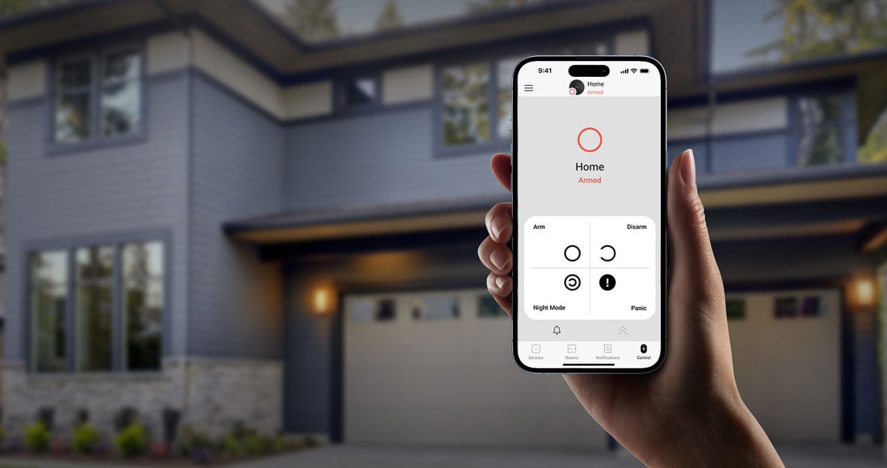 Hand holding smartphone; app shows garage door status with open/close controls; house exterior in background.