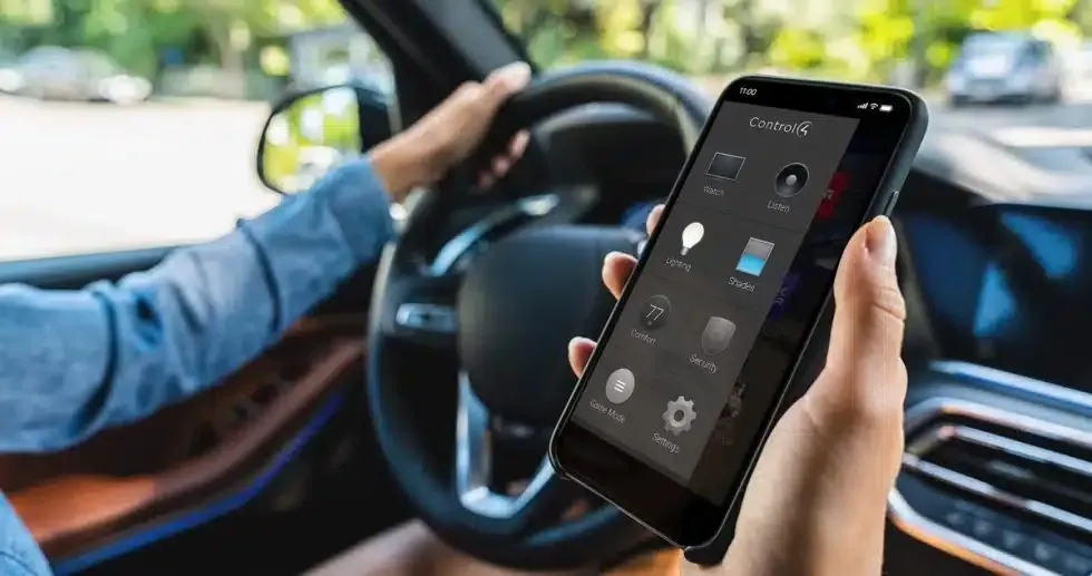 Person holding a phone with an app interface while driving a car.