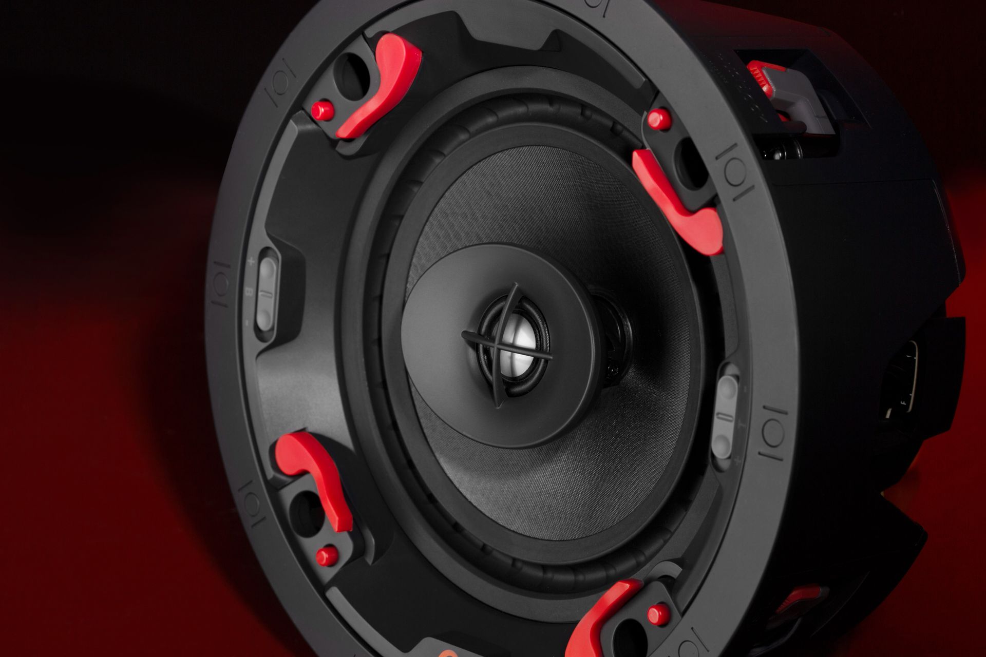 Black and red in-ceiling speaker with a circular design.