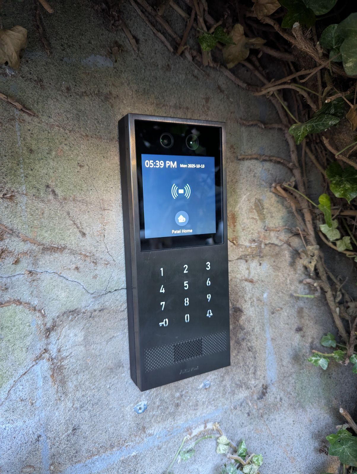 Black Eufy video doorbell mounted on a textured brick wall with a keypad, screen showing a connection icon, and camera.