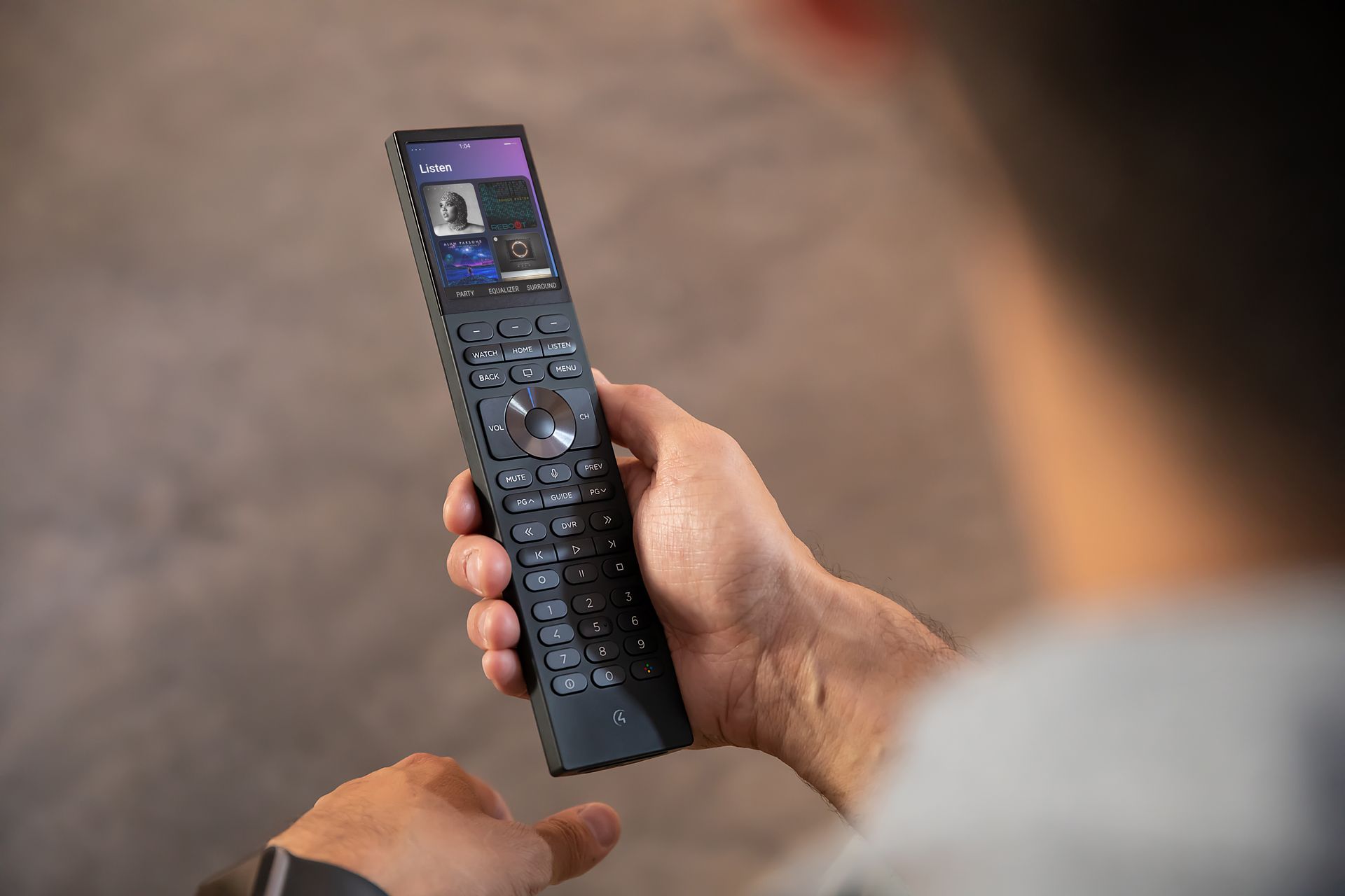 Person holding a Control4 Halo remote with touchscreen interface to manage smart home entertainment and audio systems by Rivas Technology Group.