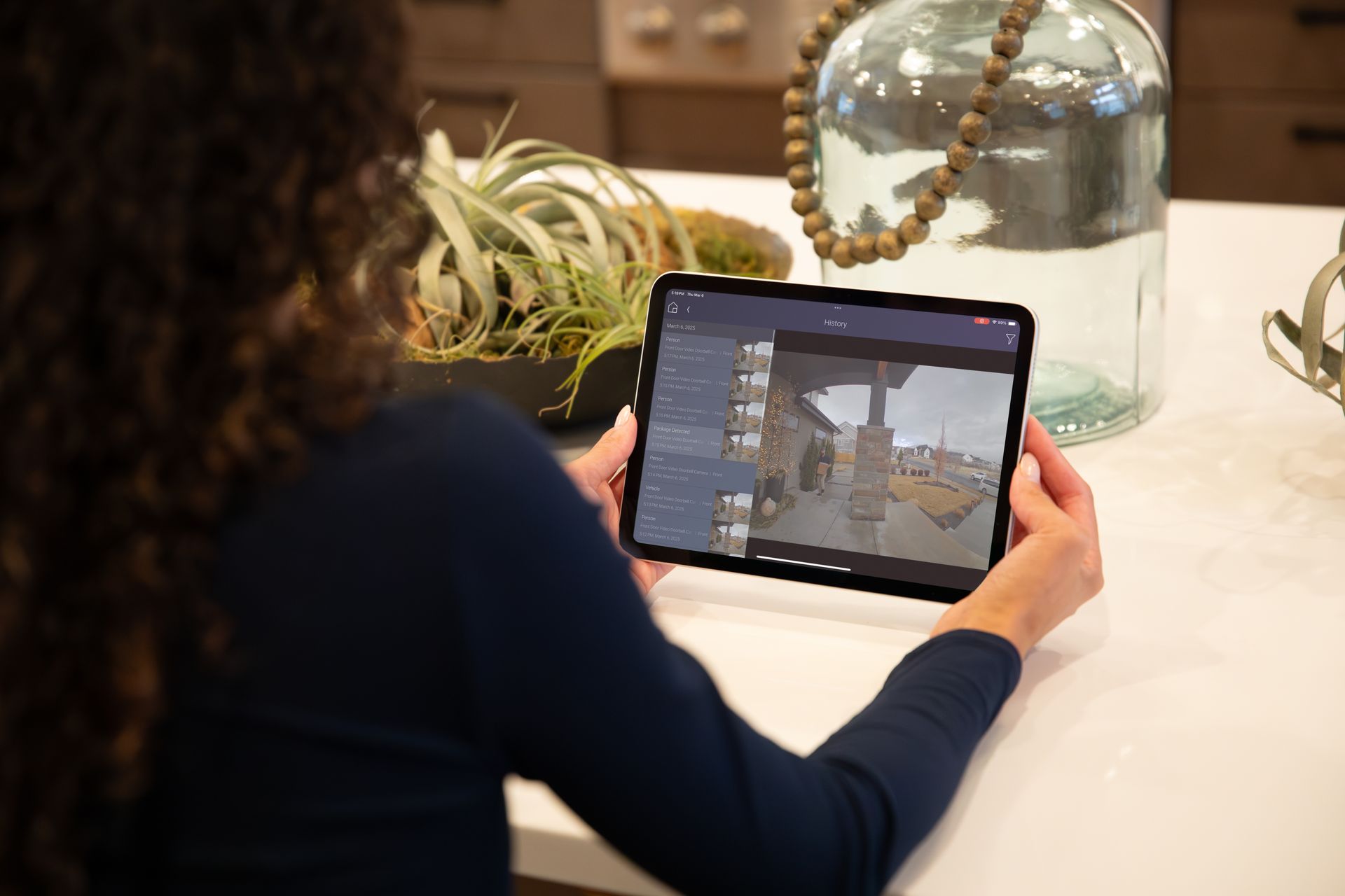 Homeowner using Control4 app on tablet to monitor smart security cameras remotely.