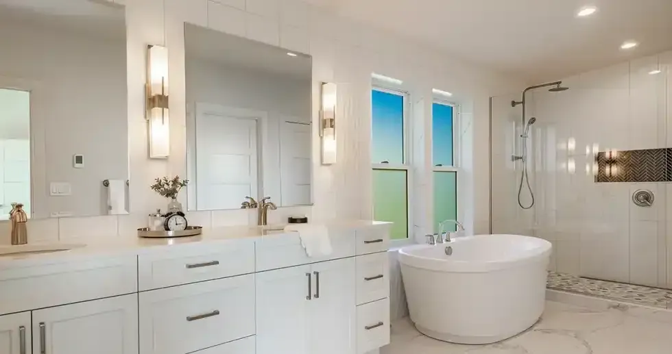 Bright white bathroom with a bathtub, shower, and vanity; windows with a blue sky view.