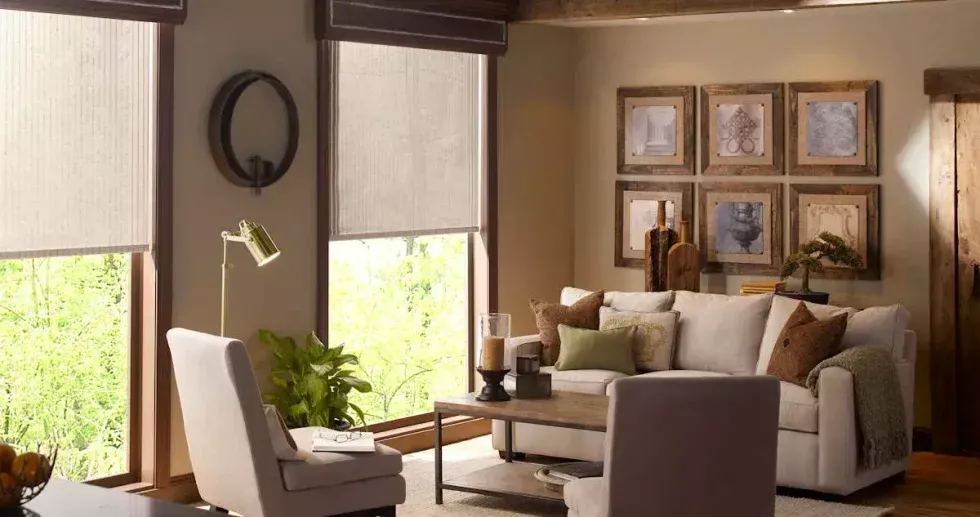 Cozy living room with cream-colored couch, framed artwork, and window shades; a warm and inviting space.