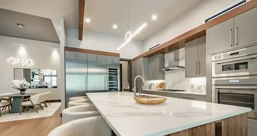 Modern kitchen with a large island, stainless steel appliances, and wood accents.
