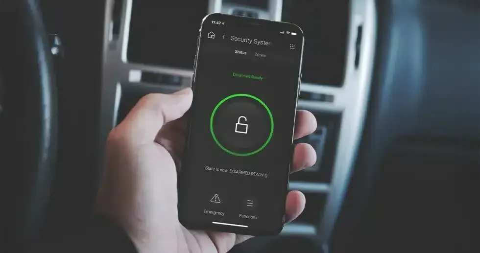 Hand holding smartphone displaying a lock icon in a car setting.