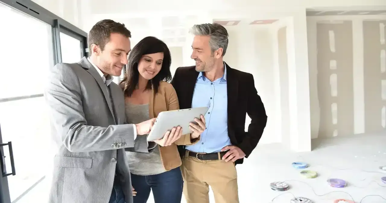 Real estate agent showing a couple a tablet inside a new construction home.