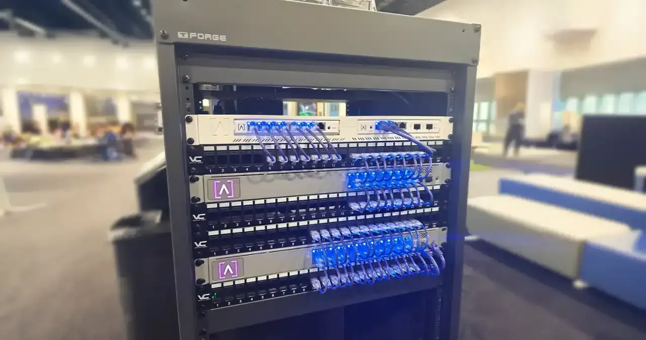 Server rack with multiple network devices and blue cables in a bright setting.