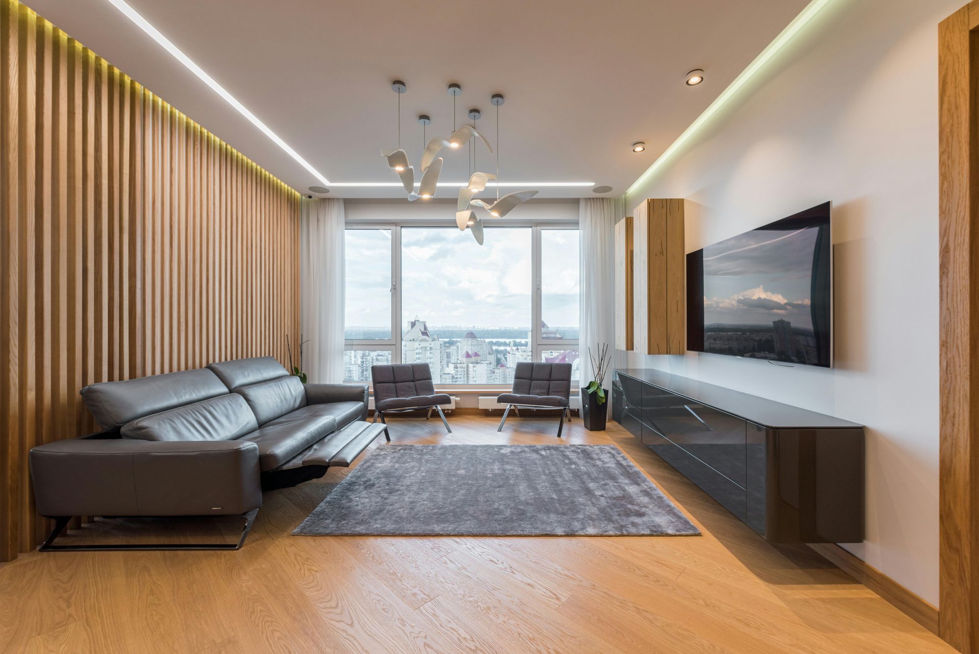Modern living room home theater with a large wall-mounted TV and clean architectural lighting.