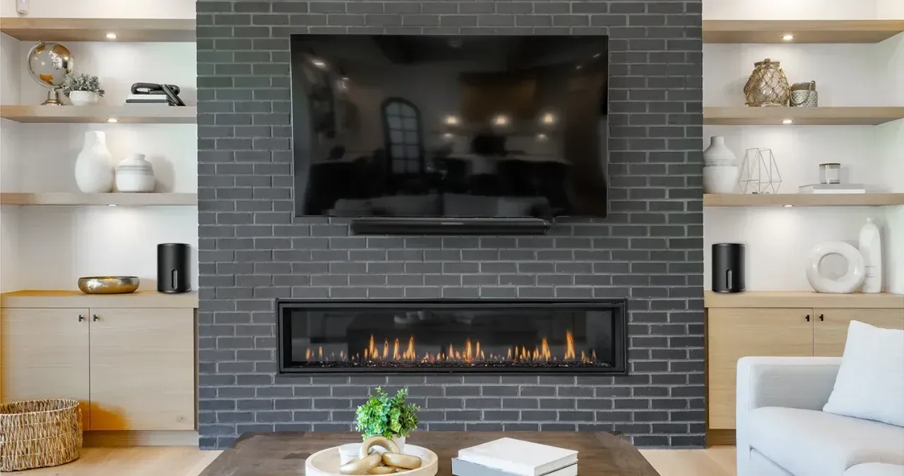 Living room with brick fireplace, TV, built-in shelves, and decorative items.
