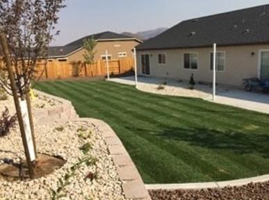 A backyard with a lush green lawn and a house in the background.