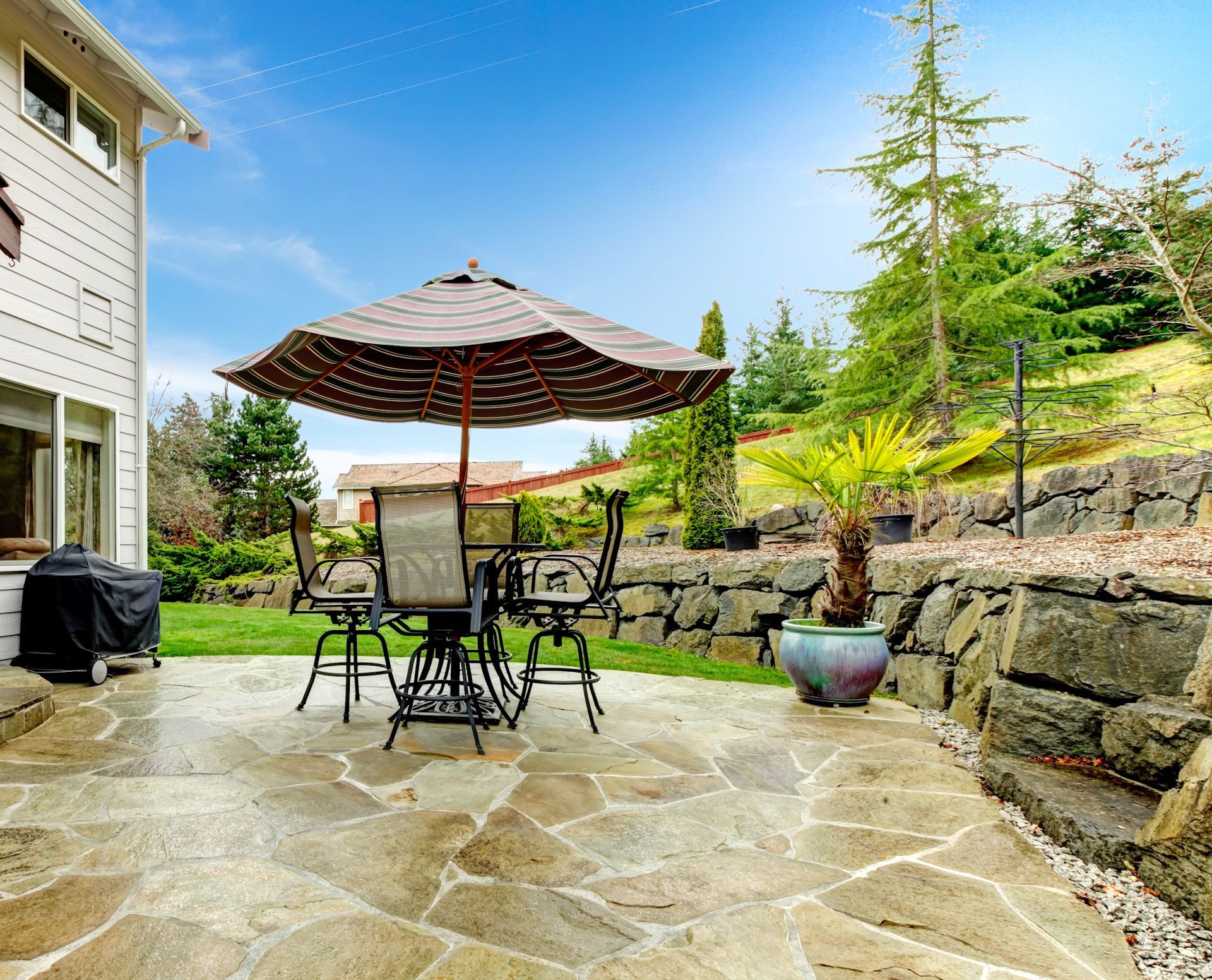 A patio with a table and chairs and an umbrella.