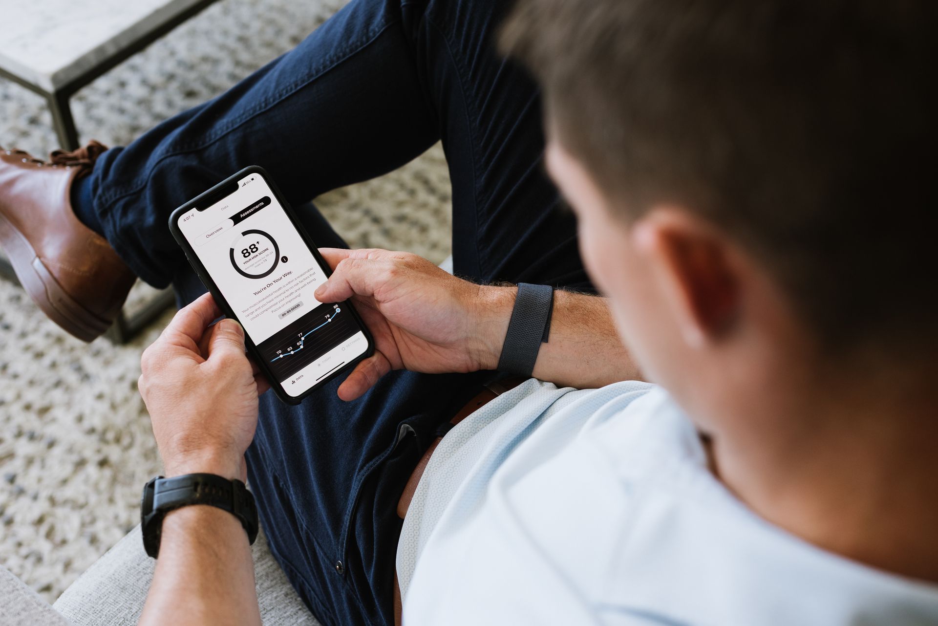 Person holding a smartphone displaying a clock while sitting on a patterned couch