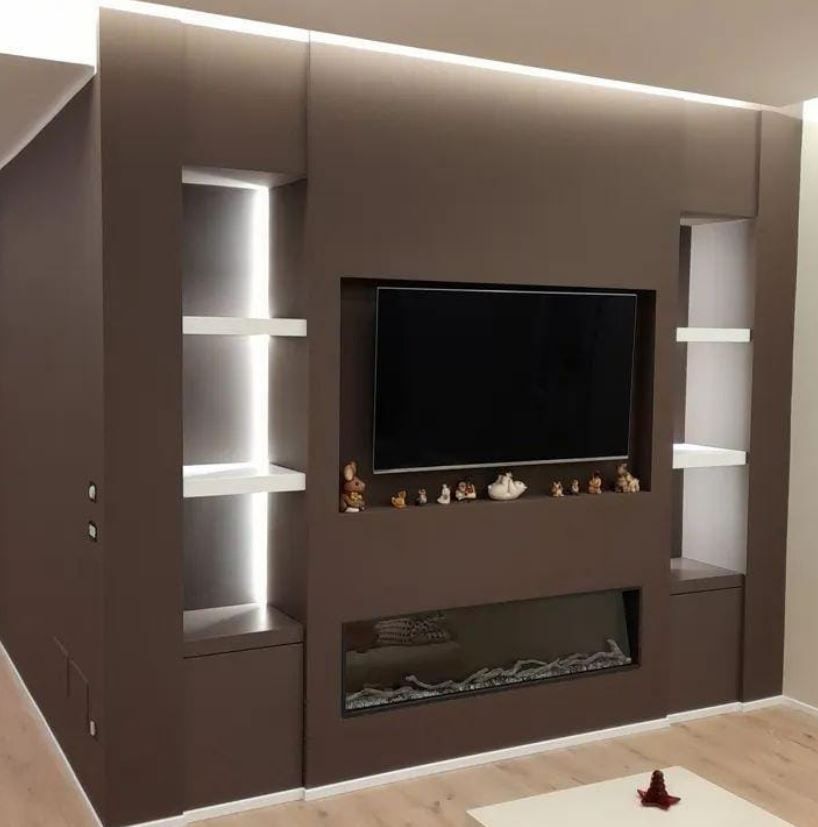 Una parete attrezzata marrone con televisore a parete, caminetto elettrico lineare e due mensole laterali illuminate.