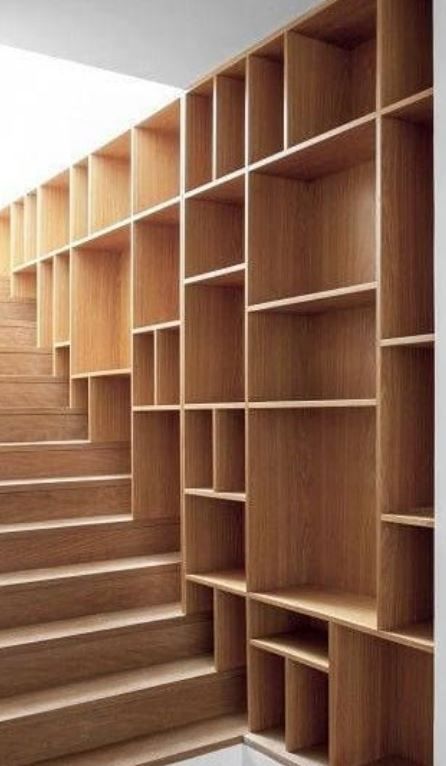 Una scala in legno con libreria integrata a tutta altezza, caratterizzata da vari scomparti verticali e orizzontali.
