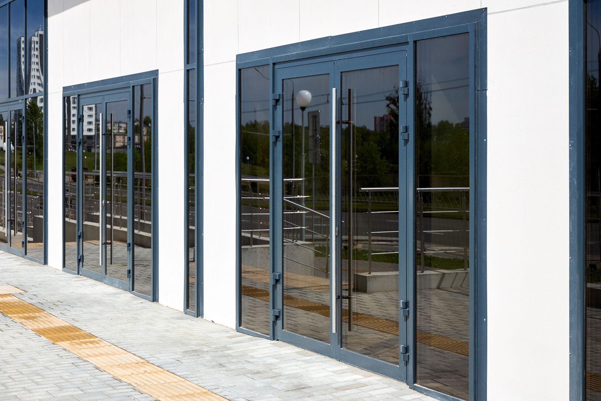 Blue-framed commercial storefront glass entrance with double glass doors and large display windows. Blue-framed commercial storefront glass entrance with double glass doors and large display windows.