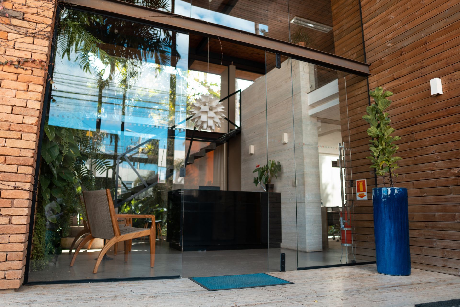 Glass door with a potted plant beside it, showcasing a modern storefront glass installation.