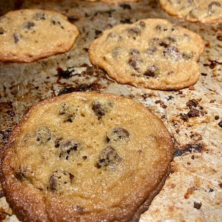 A bunch of organic gluten free chocolate chip cookies are sitting on a pan.