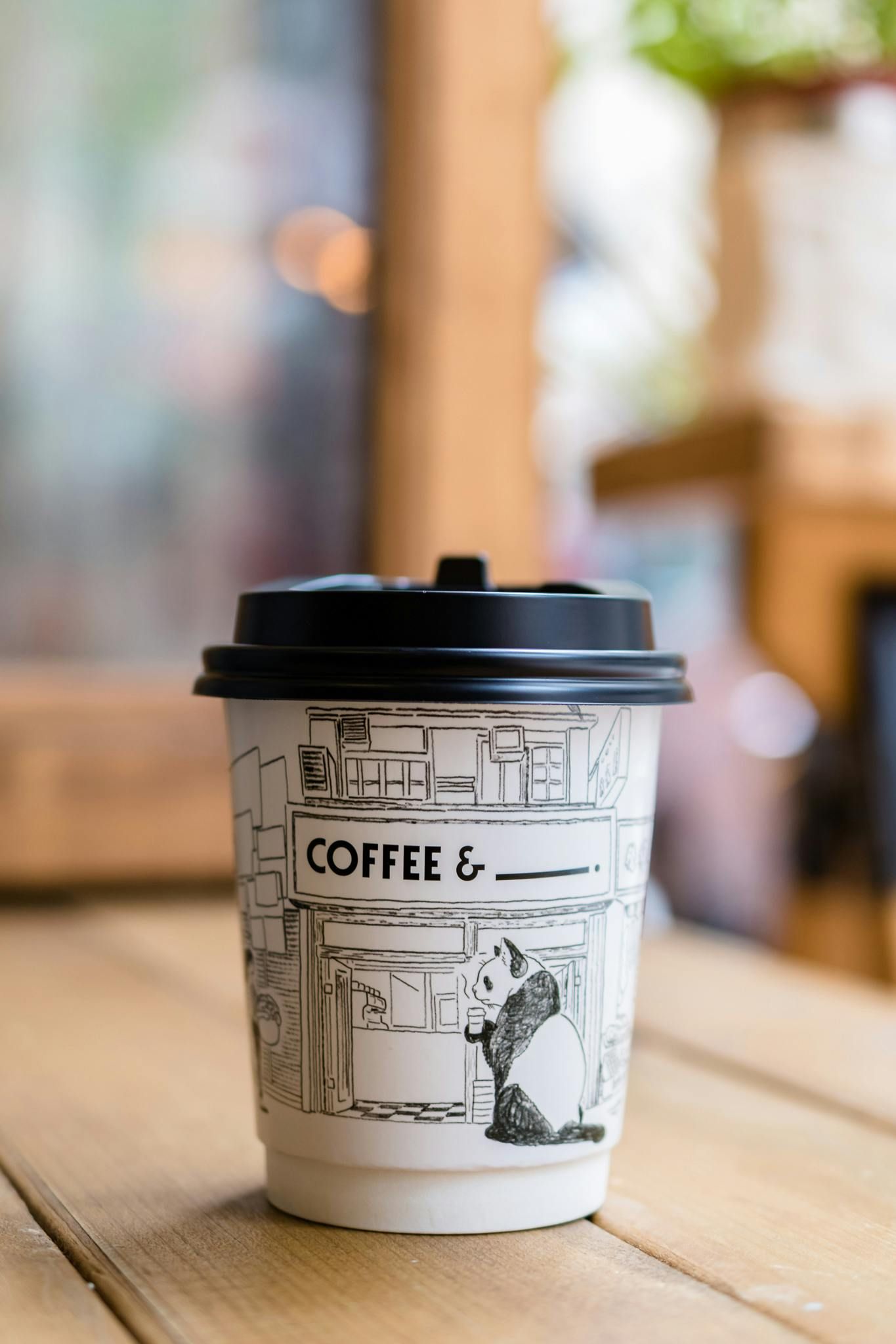 A cup of coffee is sitting on a wooden table.