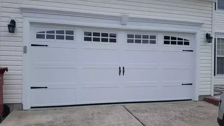 A white garage door is open in front of a white house.