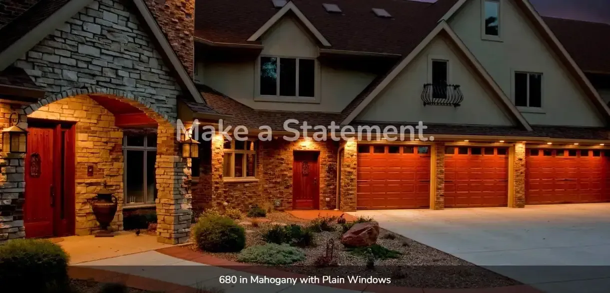 A large house with red garage doors is lit up at night.