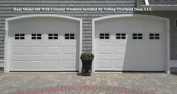 A picture of two white garage doors with a potted plant in front of them