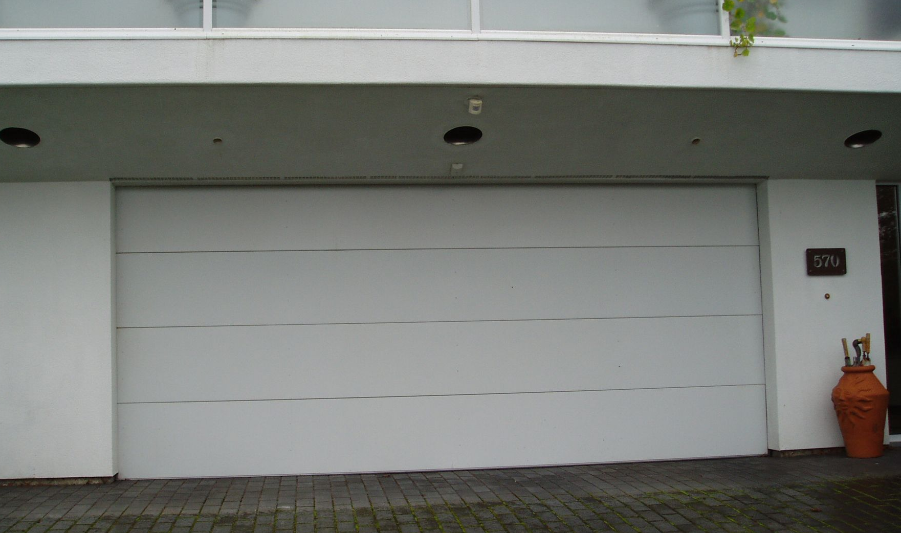 A white garage door is sitting in front of a white building.