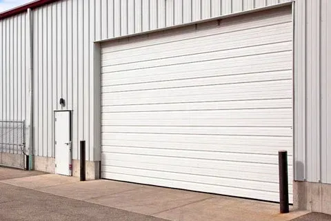 A white garage door is open on the side of a building.