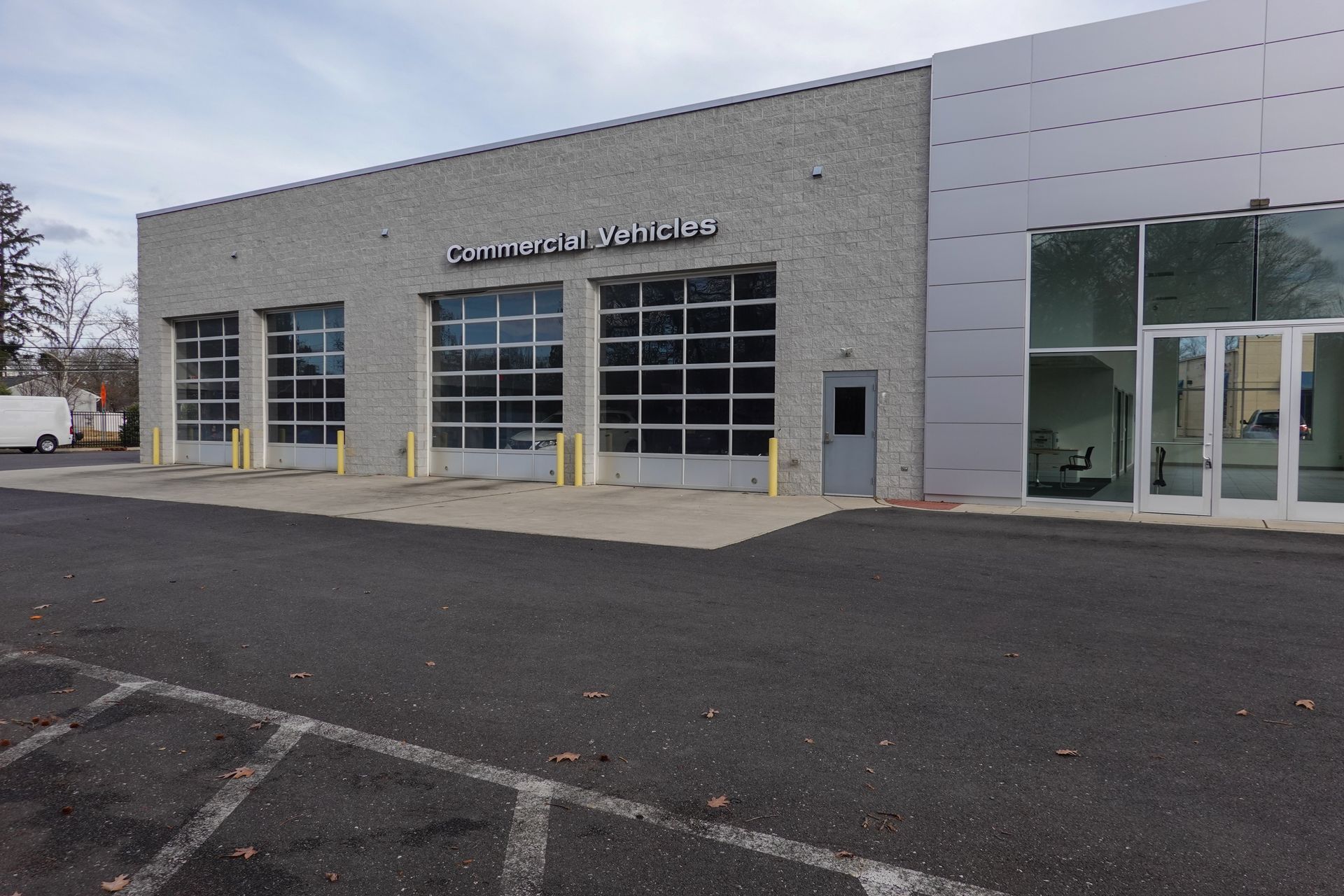 Modern auto service building with large garage doors and a glass entrance on an overcast day