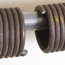 A close up of a garage door spring on a white surface.