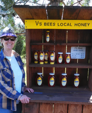 Hands removing a honeycomb frame with bees from a beehive box