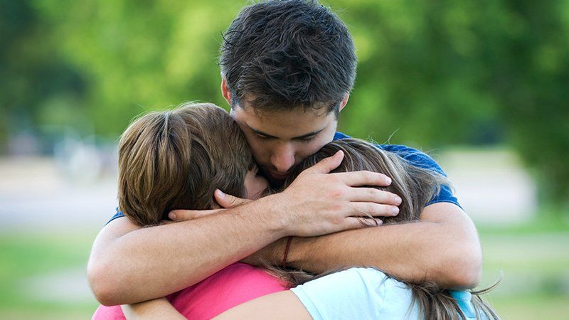 man hugs two children