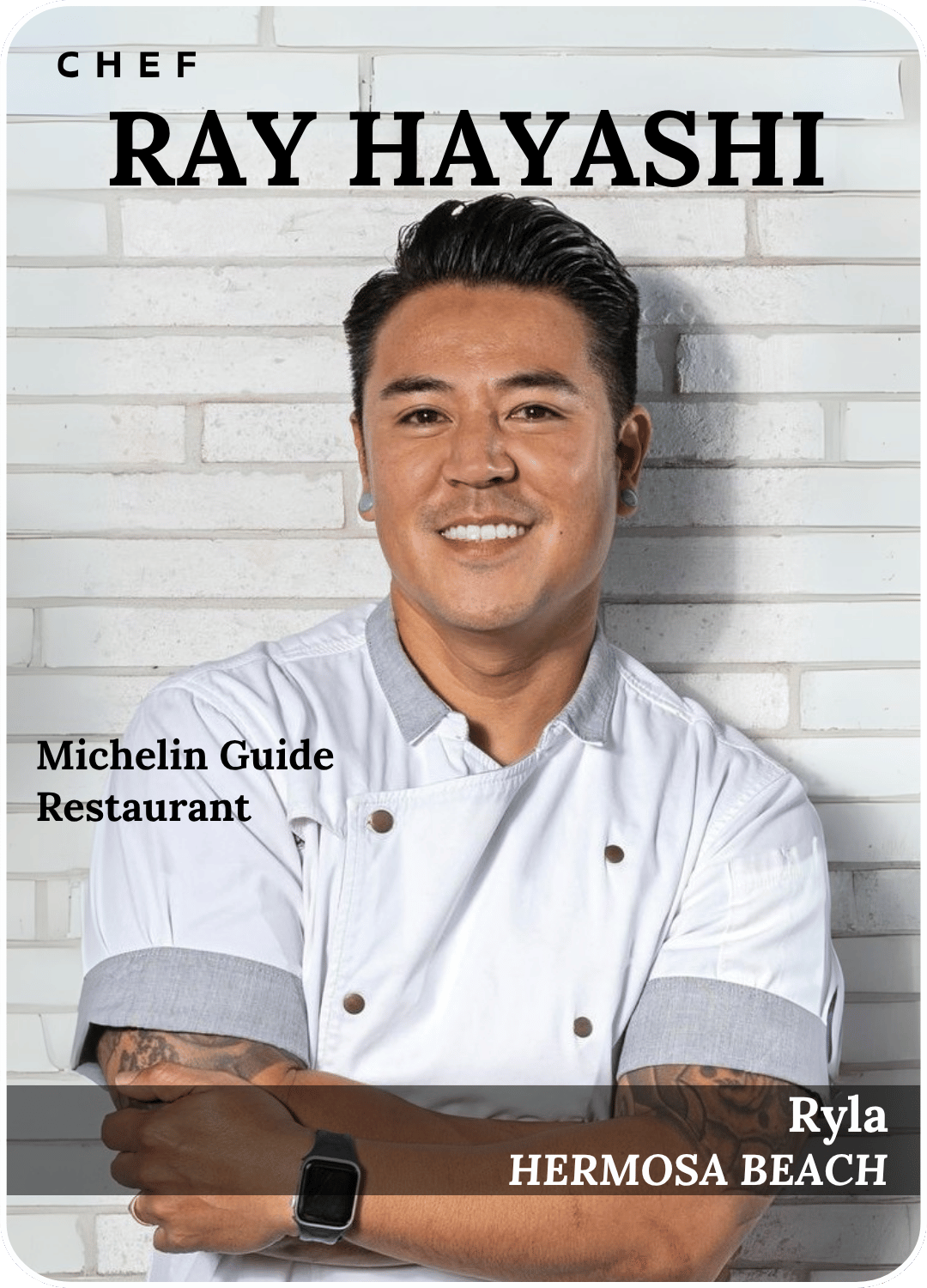 Chef Ray Hayashi smiling in a white chef coat against a white brick wall