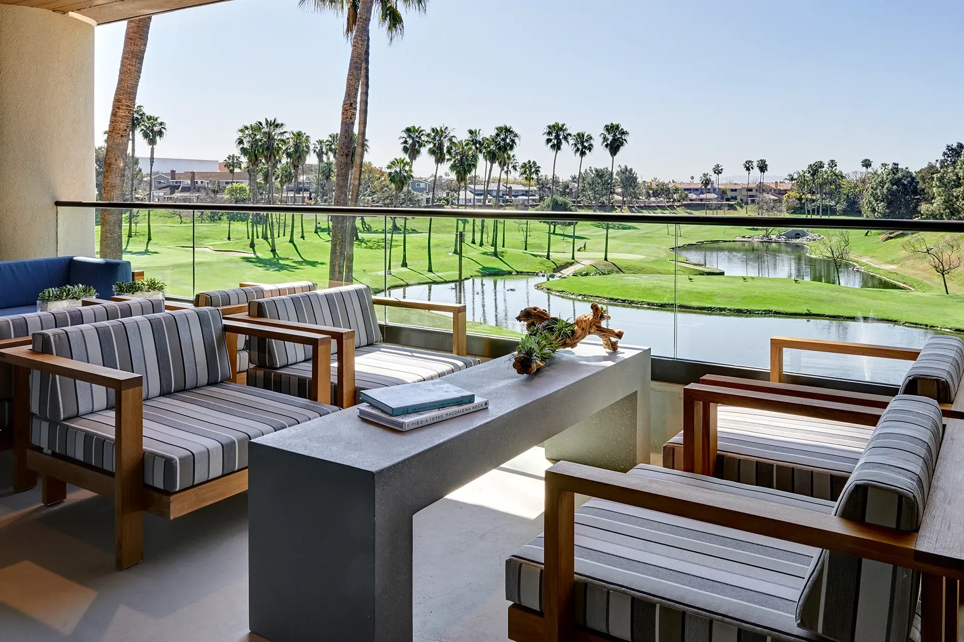Outdoor patio seating overlooking a green golf course and palm trees