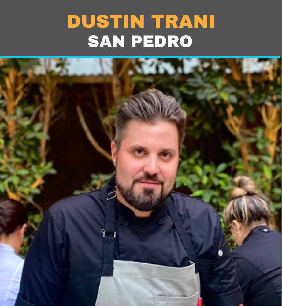 Chef Dustin Trani in a black jacket and gray apron, standing outdoors at San Pedro restaurant.