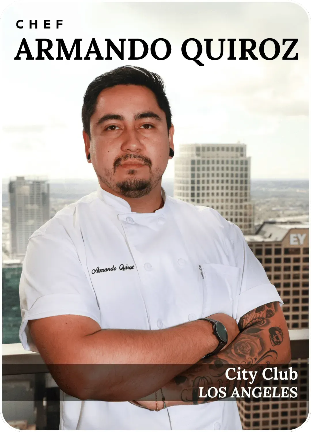 Chef Armando Quiroz in white chef coat, standing with arms crossed against a city skyline
