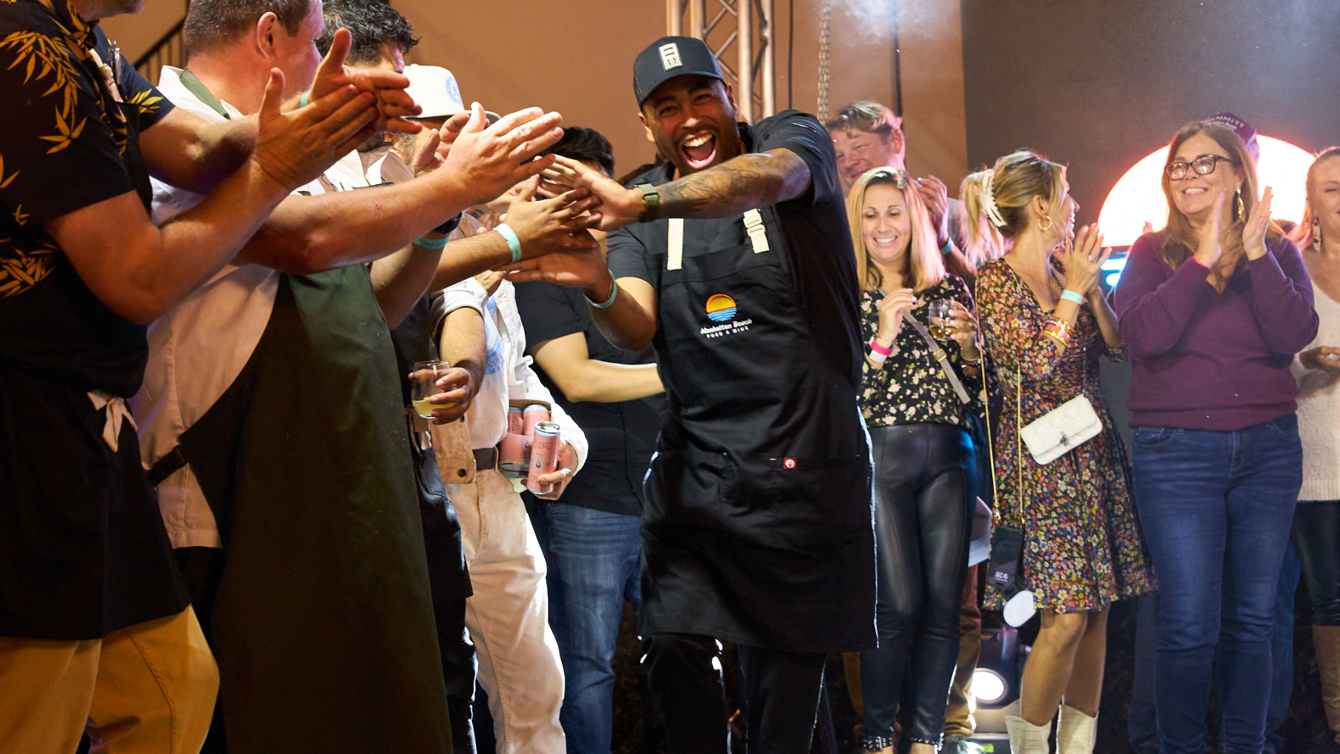People clapping around a man in black performing a dance in a crowded indoor event