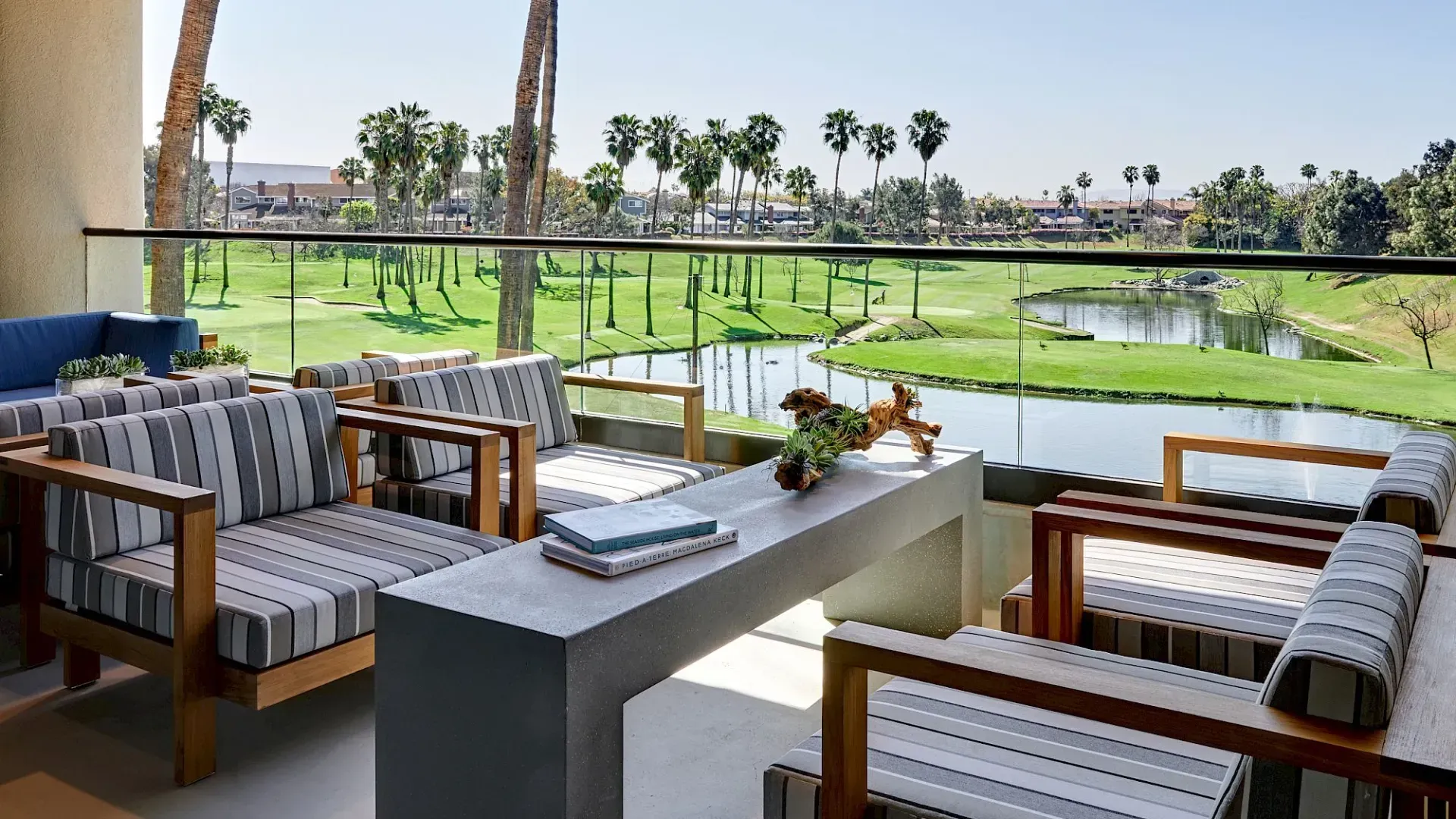Patio seating overlooking a green golf course under a clear sky